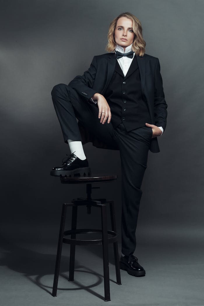 Stylish portrait of a well-dressed woman posing in formalwear against a neutral studio backdrop.